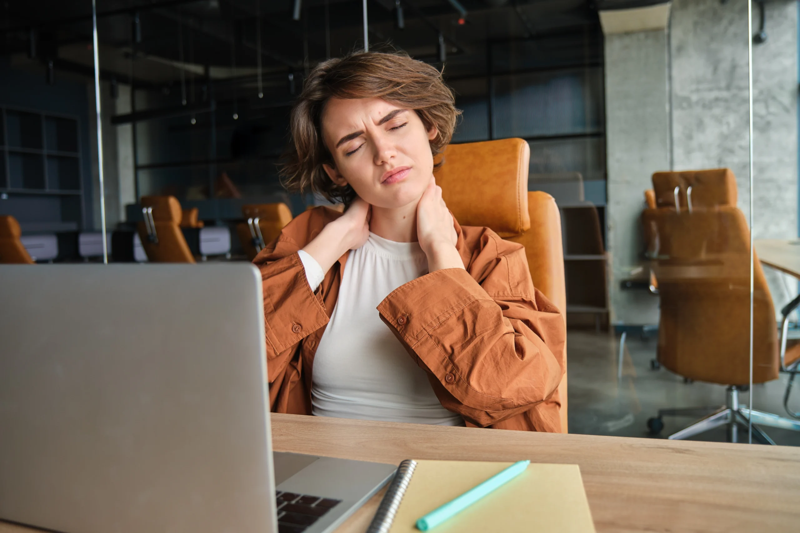 image woman with tired face sits with laptop office feels tension neck pain muscles